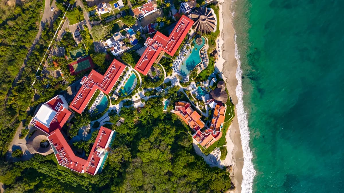 Overhead drone view of the full Armony Marival resort complex nestled between jungle and ocean along the Riviera Nayarit coastline