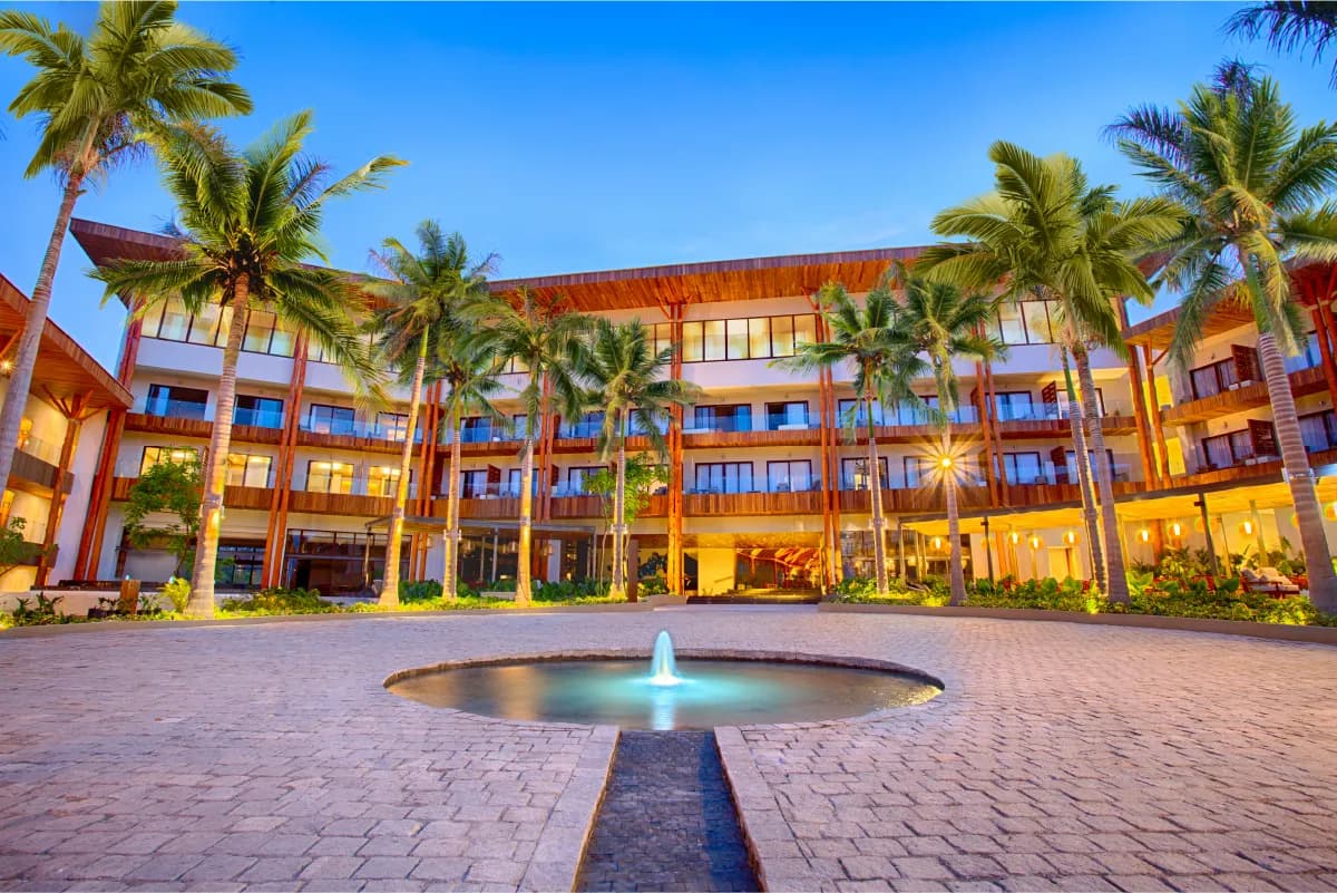 The main building courtyard at dusk featuring a central fountain surrounded by palm trees and warm lighting