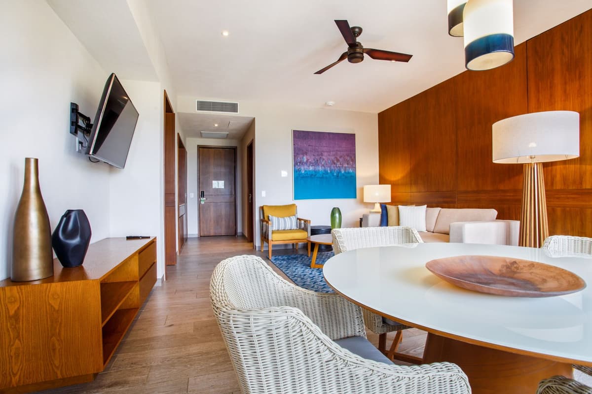 Spacious suite living and dining area with contemporary furnishings, ceiling fan, and warm wood paneling