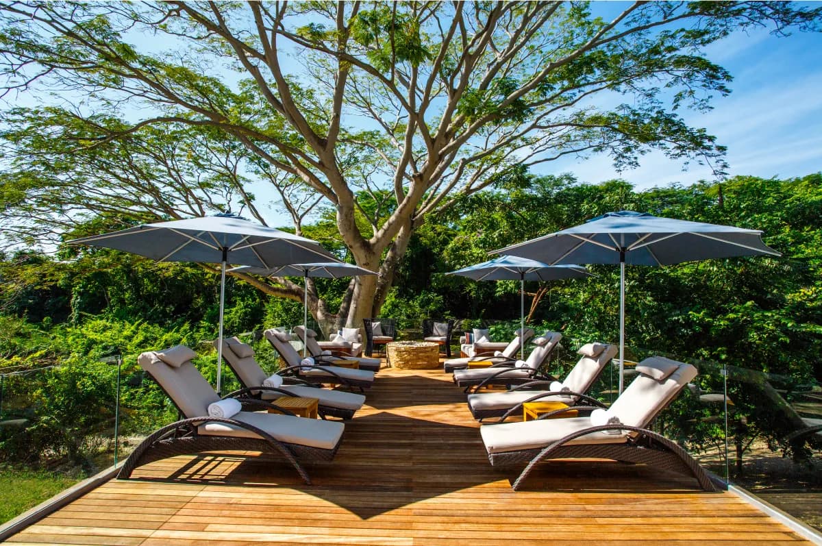 Melange Spa relaxation deck surrounded by lush jungle canopy with cushioned loungers and parasols