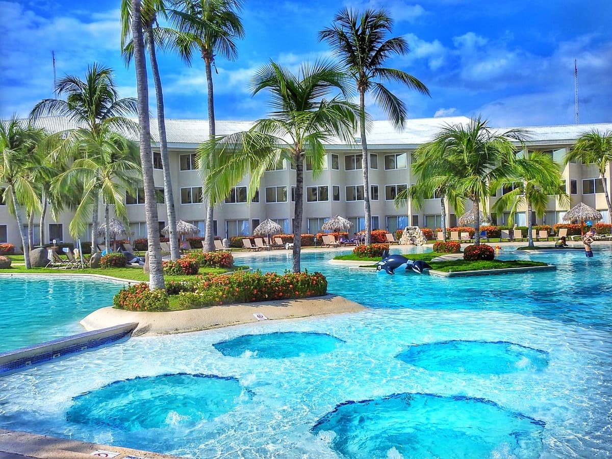 Main swimming pool with arched bridge, swim-up bar, and surrounding loungers at Fiesta Resort