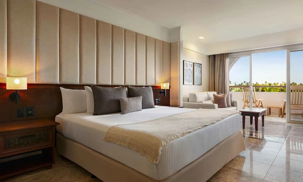 Junior Suite Garden View with king bed, contemporary furnishings, and private balcony overlooking lush gardens