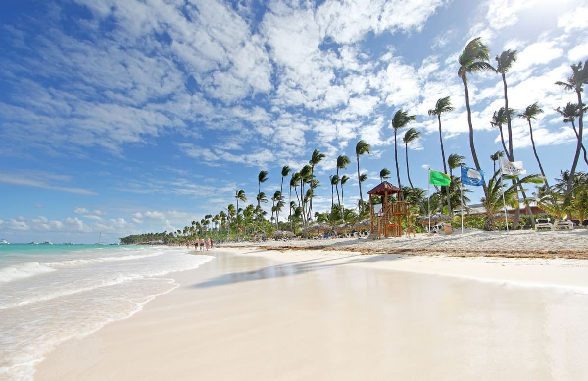 Blue Flag-certified Bavaro Beach stretching along the Grand Palladium complex with calm Caribbean waves and beach bar kiosks