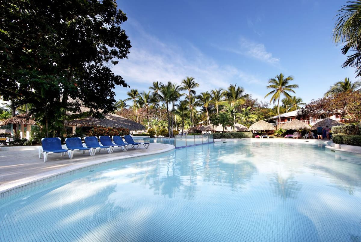 Main swimming pool at Grand Palladium Palace with swim-up bar, sun loungers, and tropical landscaping