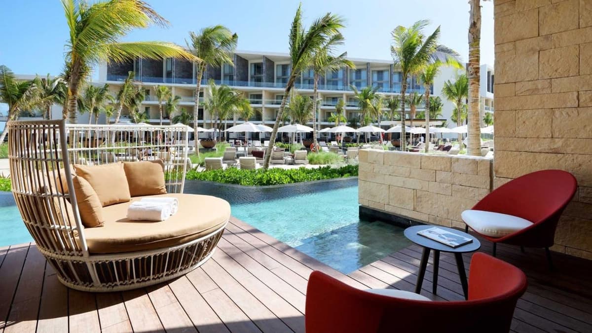 Pool area with modern resort architecture, palm trees, and Caribbean blue water views at Grand Palladium Select Costa Mujeres