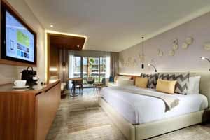 Junior Suite Garden/Lagoon View with king bed, modern decor, 50-inch flat-screen TV, and furnished balcony