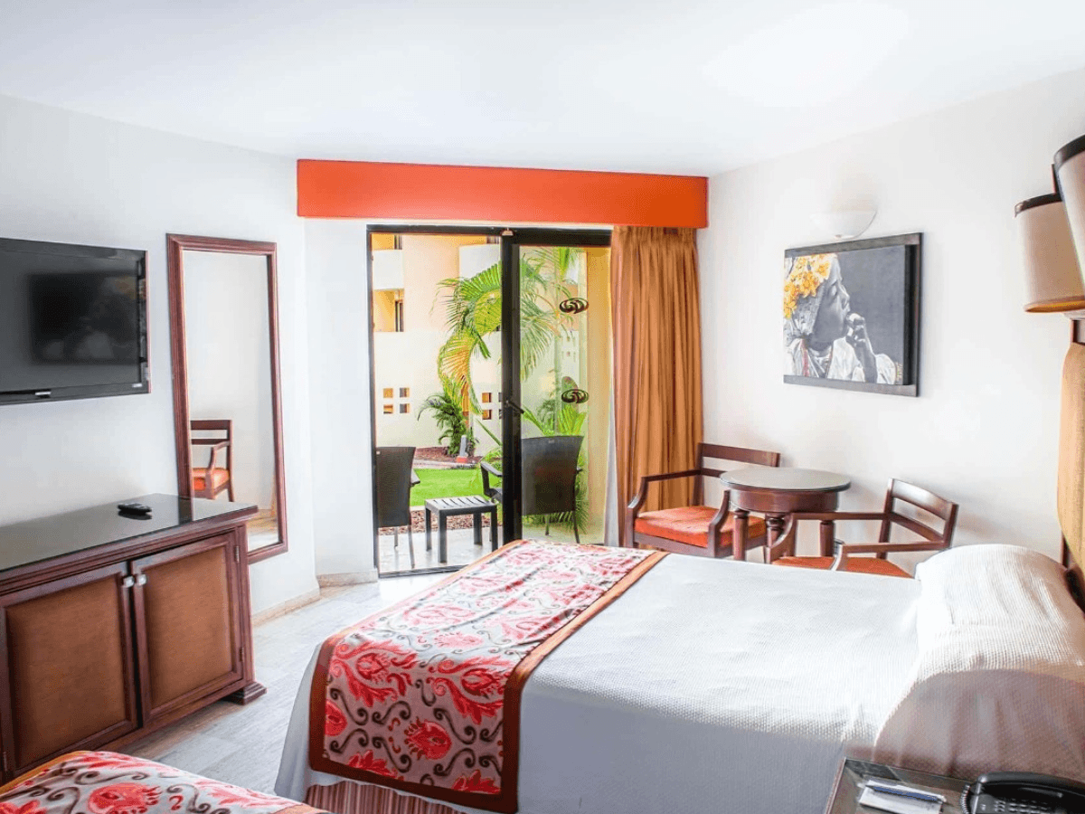 Deluxe Garden View room with king bed, dark-wood furnishings, and furnished terrace