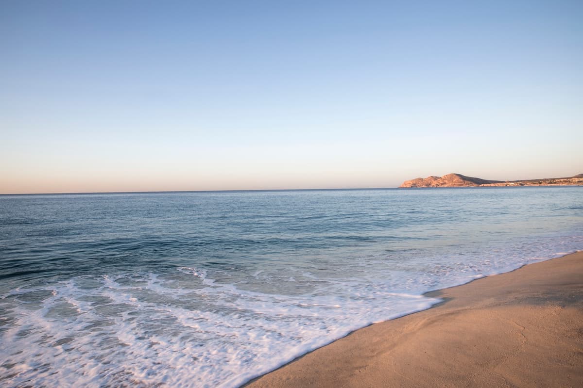 Golden sandy beach at sunset with Sea of Cortez and mountain silhouette