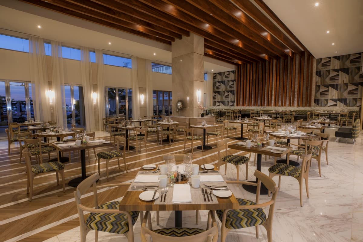 Main restaurant with soaring ceilings, wood beam details, and ocean-view windows