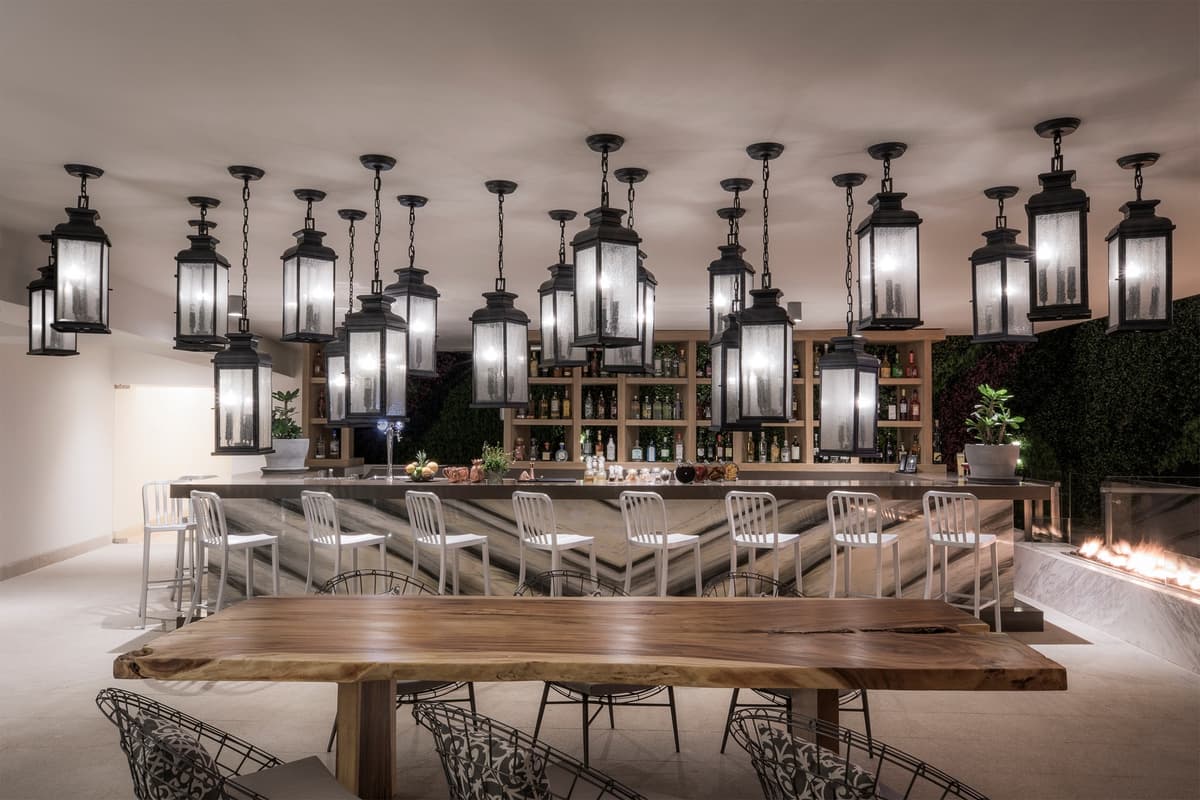 Outdoor bar with hanging lanterns, marble counter, and live-edge wood table