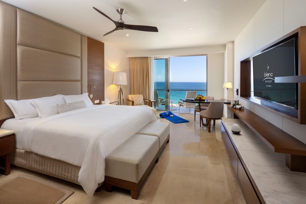 King bedroom suite with ocean view, ceiling fan, and warm wood accents