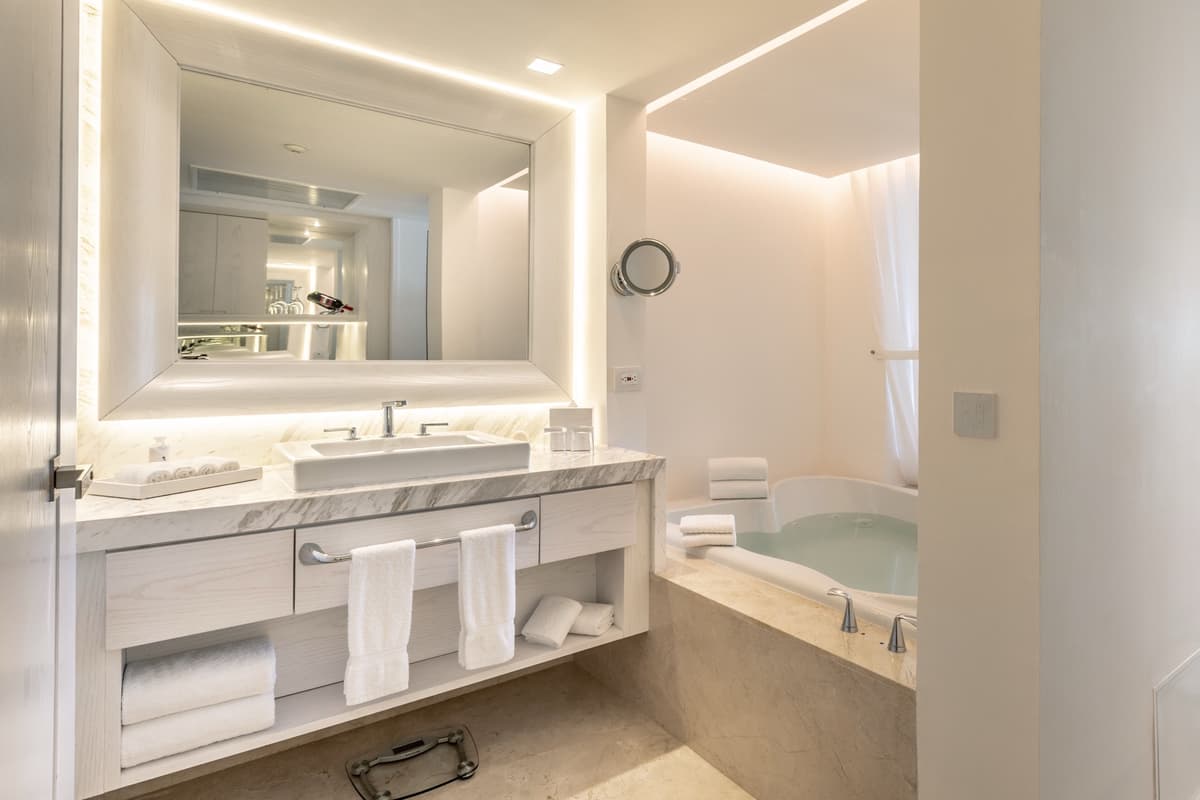 Marble bathroom with backlit mirror, double vanity, and soaking tub