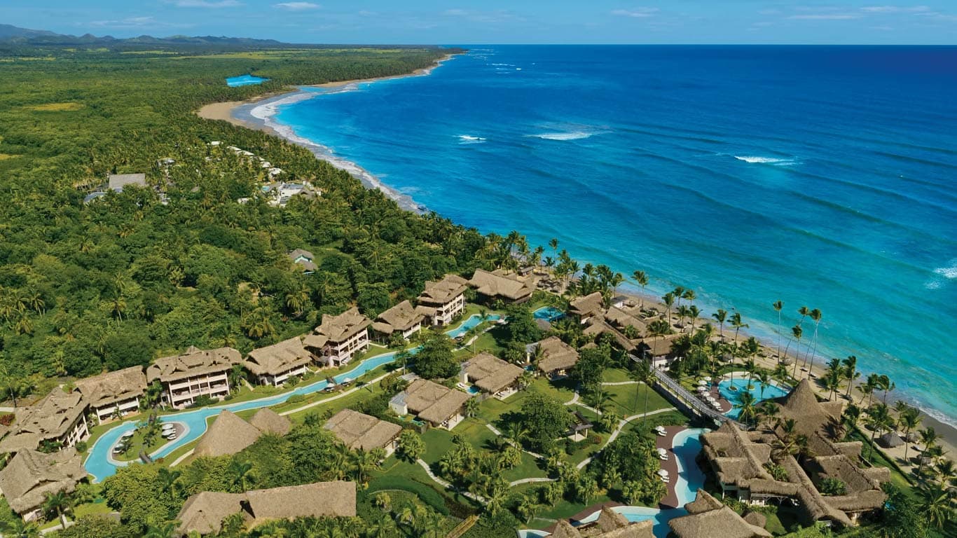 Aerial panorama showing the resort nestled between lush tropical vegetation and the turquoise Caribbean Sea along the Uvero Alto coast