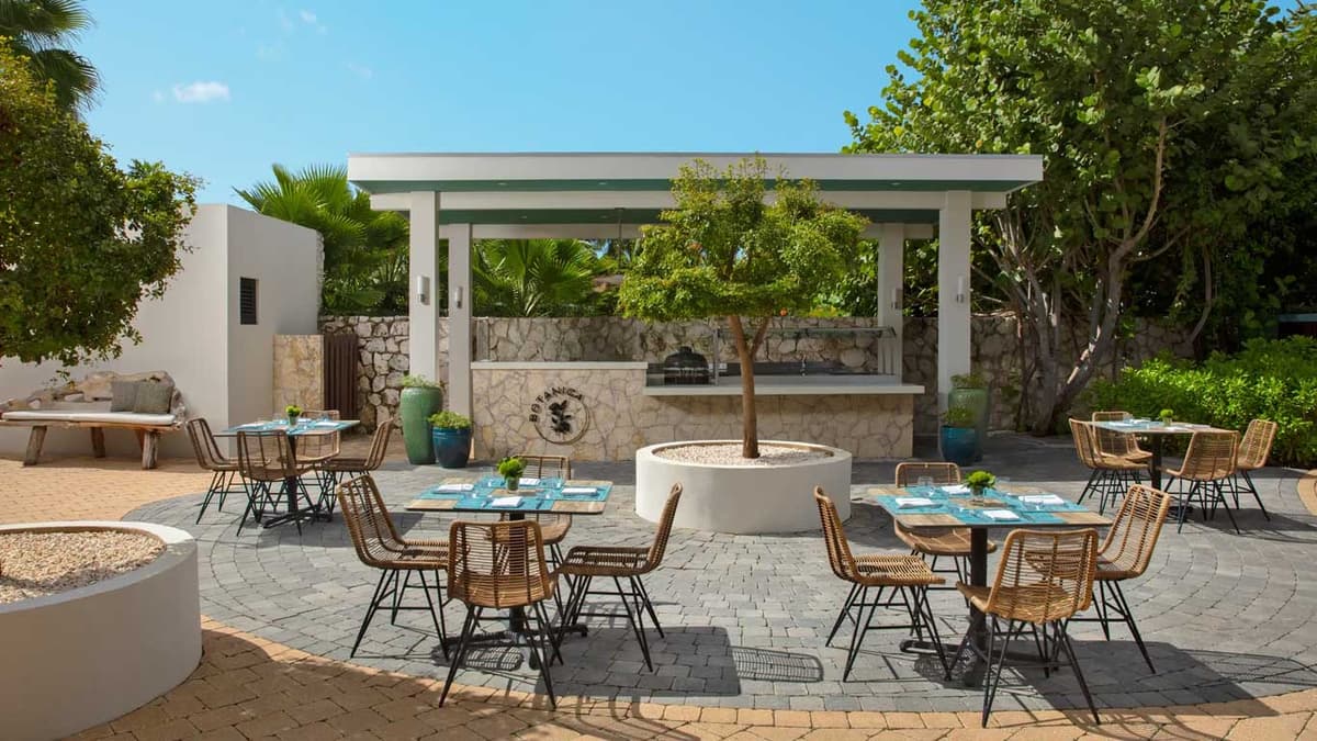 Botanica open-air grill restaurant with stone-and-wood bar surrounded by tropical trees