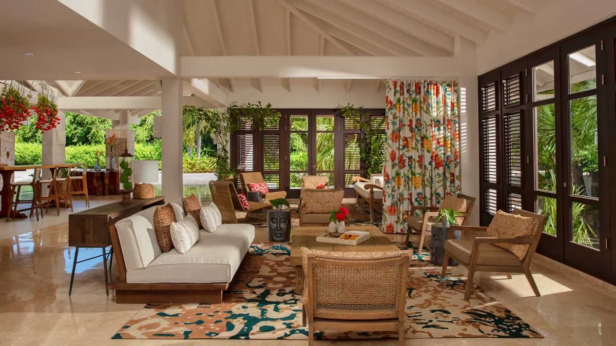 Open-air lobby lounge with tropical floral curtains, woven rattan furniture, and natural wood accents