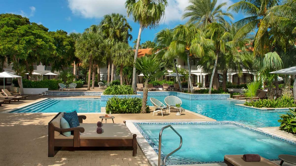 Multi-level pool area with wooden daybeds and lush tropical landscaping