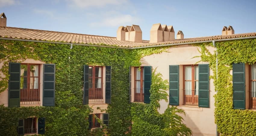 Historic Sa Torre manor house facade with ivy-covered stone walls and traditional Mallorcan green shutters