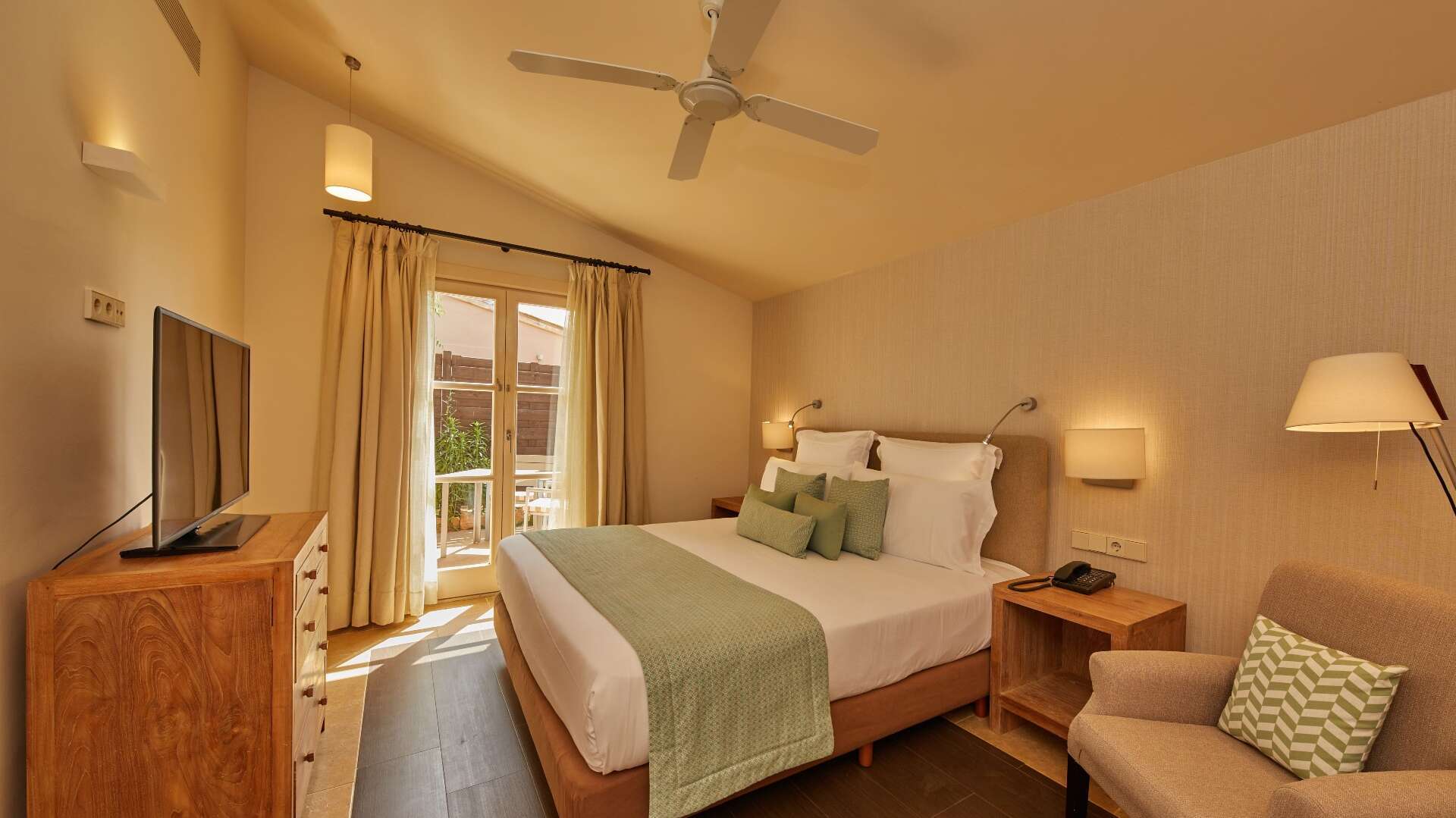 Suite Ponent bedroom with king bed, vaulted ceiling with fan, natural wood furniture, and French door terrace access