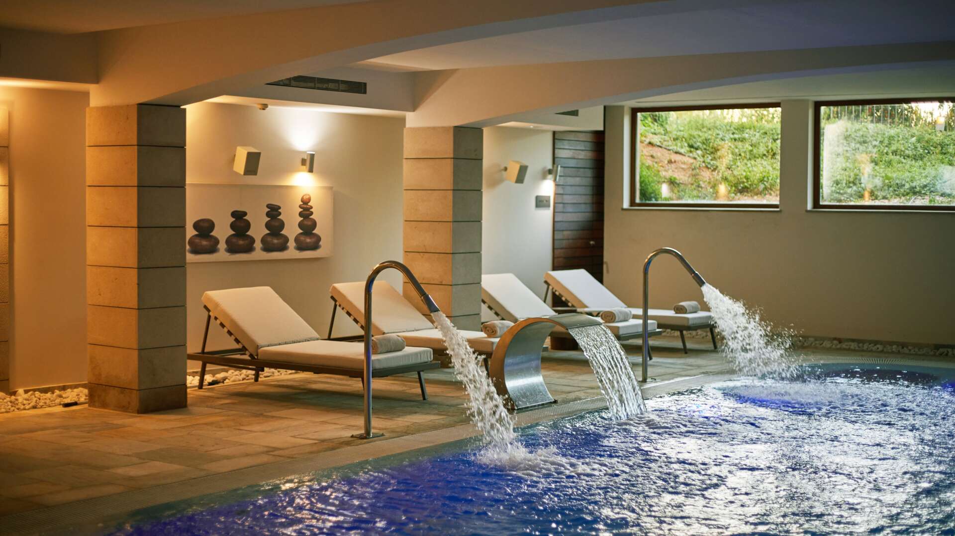 Pure Spa by Natura Bisse indoor hydrotherapy pool with swan-neck water features and loungers under vaulted ceilings