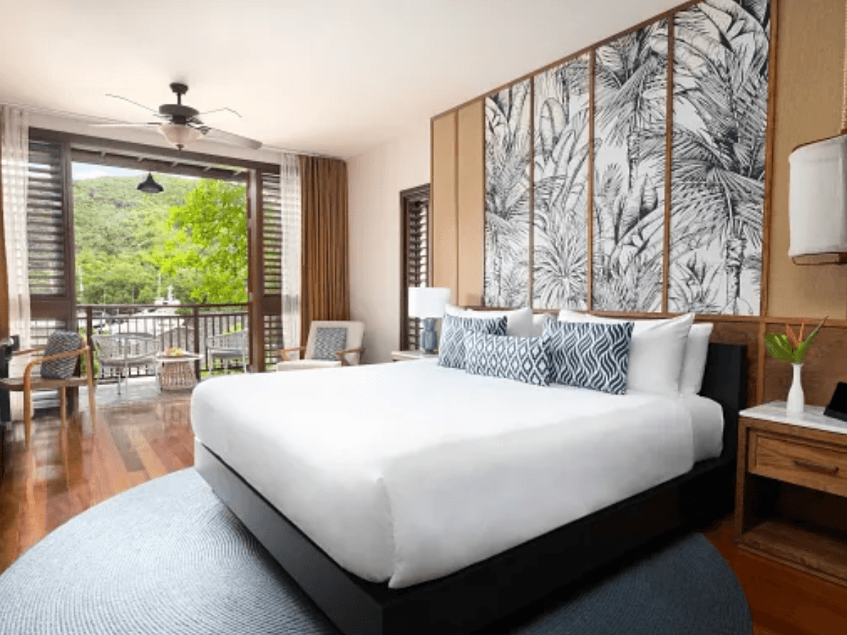 Junior Suite Garden View bedroom with organic wood tones, louvered doors, and lush garden outlook