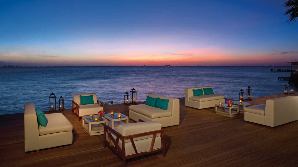 Oceanfront lounge deck at sunset with views across to the Cancun Hotel Zone skyline
