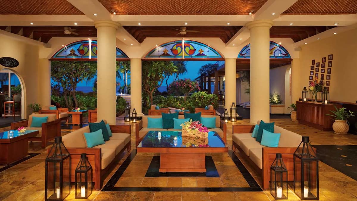Resort lobby and lounge with stained-glass arches, warm wood furniture, and tropical garden views