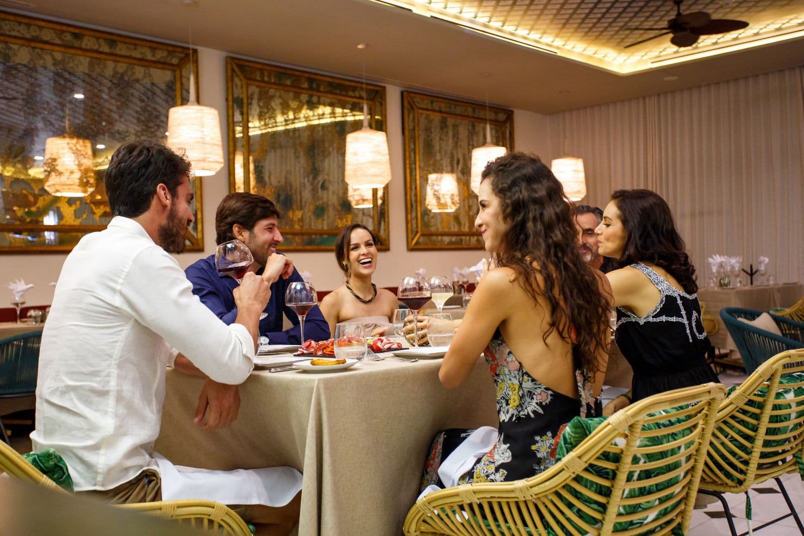 Beachfront restaurant terrace with ocean views, elegant table settings, and thatched palapa roof at sunset