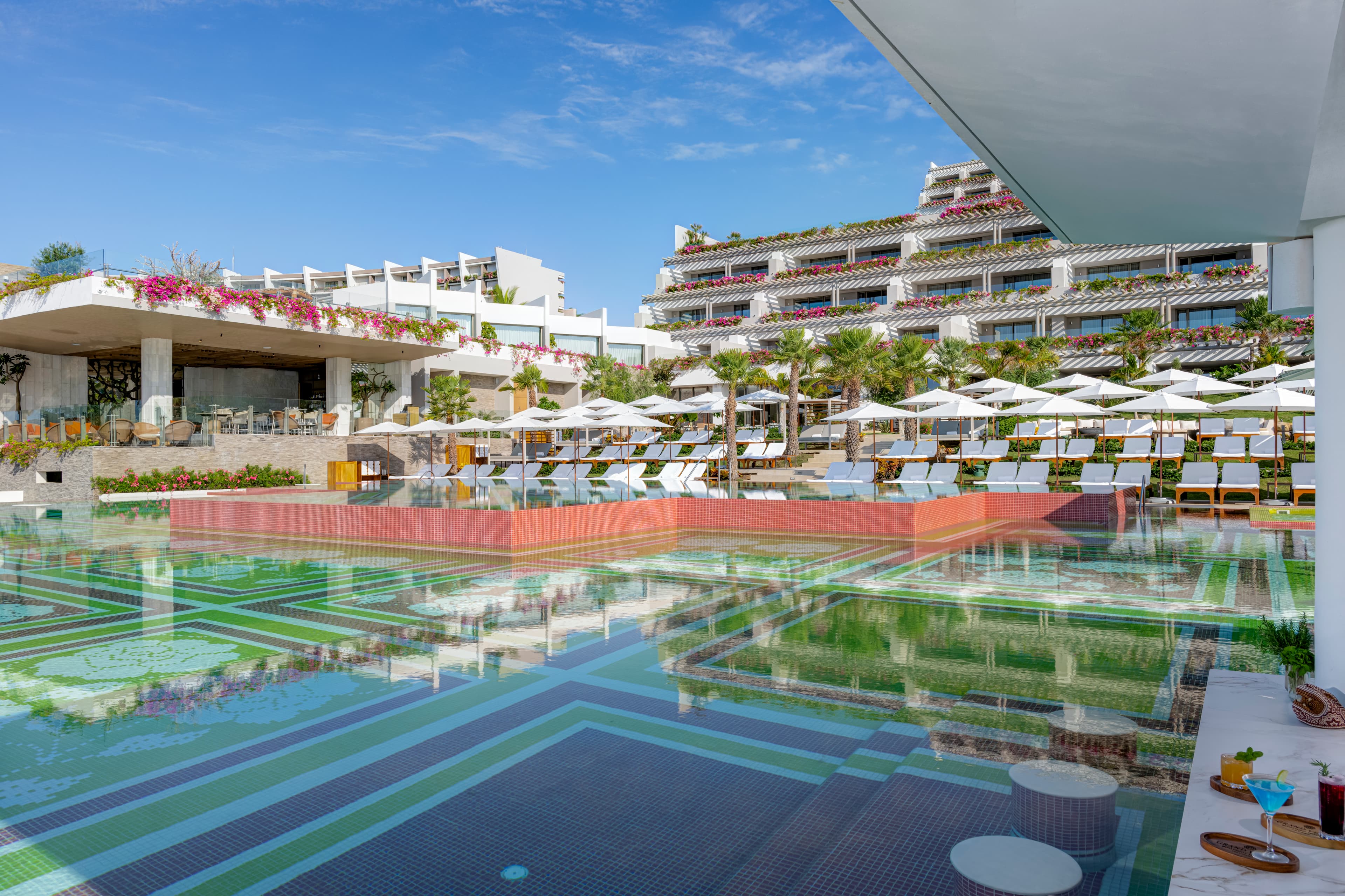 Infinity pool with colorful mosaic tiles and loungers overlooking the ocean