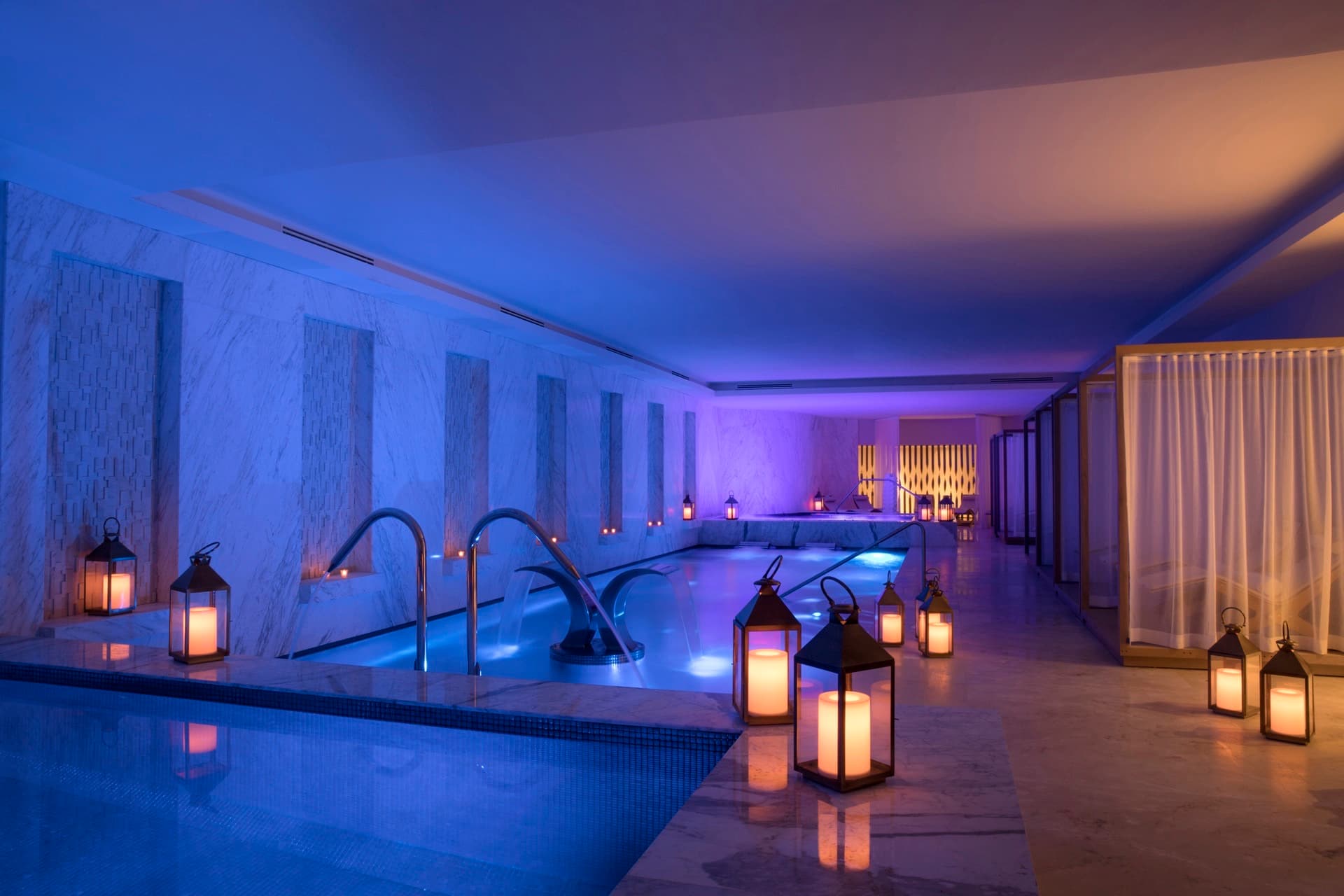 Spa hydrotherapy circuit with blue ambient lighting, lanterns, and plunge pools
