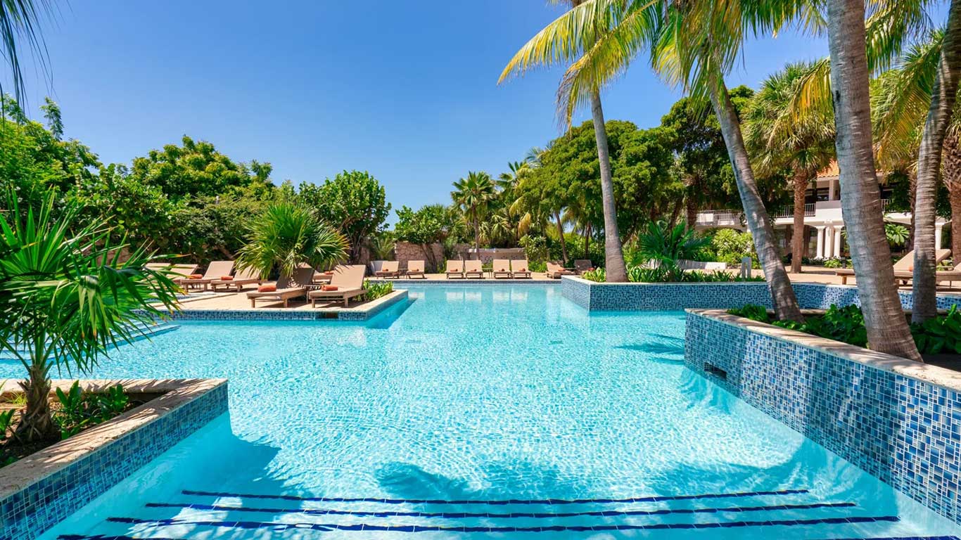 Main resort pool with turquoise mosaic tiles and palm tree-lined loungers