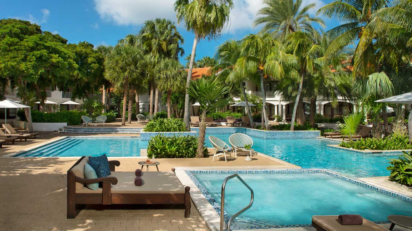 Multi-level pool area with wooden daybeds and lush tropical landscaping
