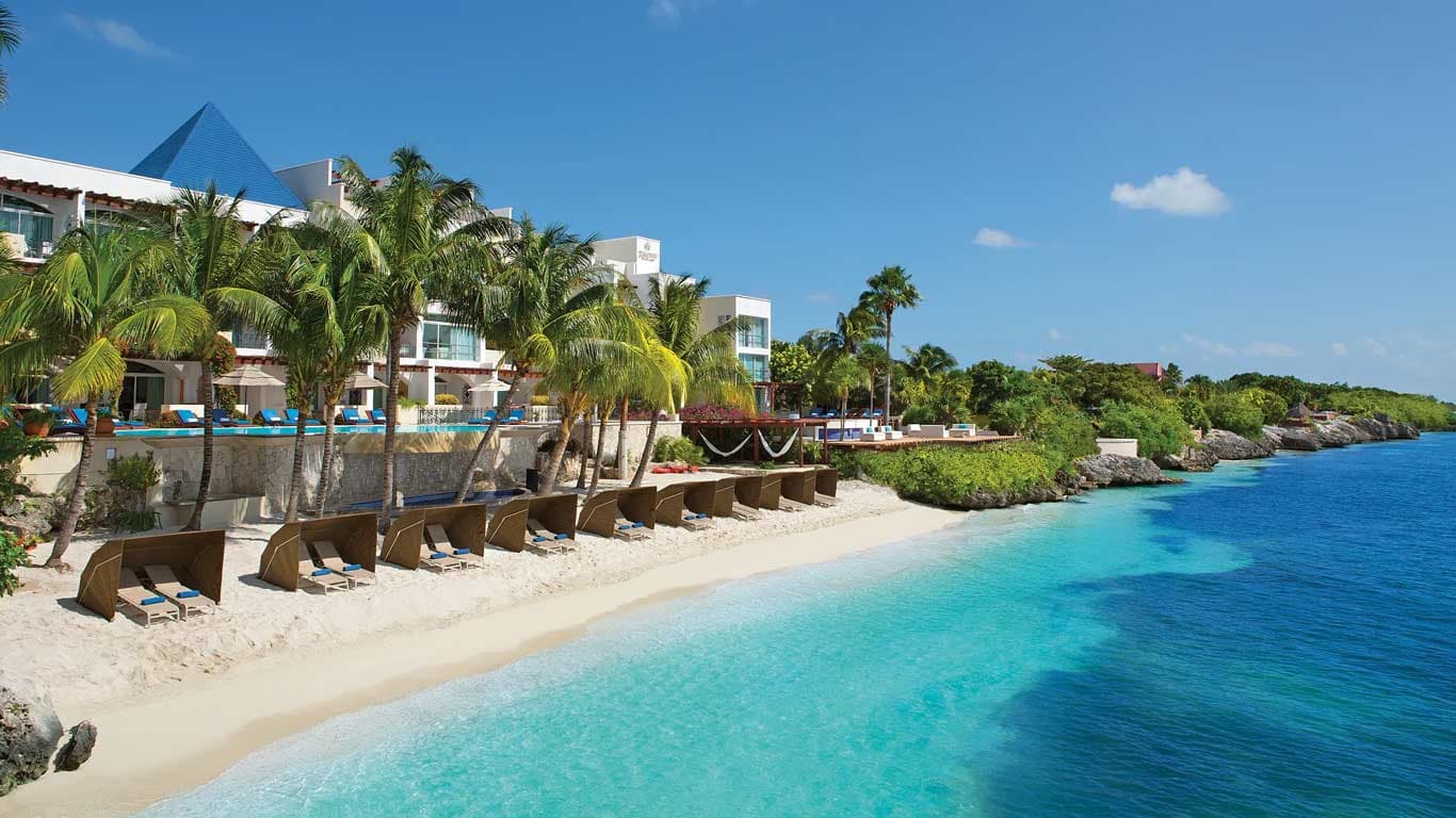 Private beach with wooden privacy screens and blue-cushioned loungers on the Caribbean Sea