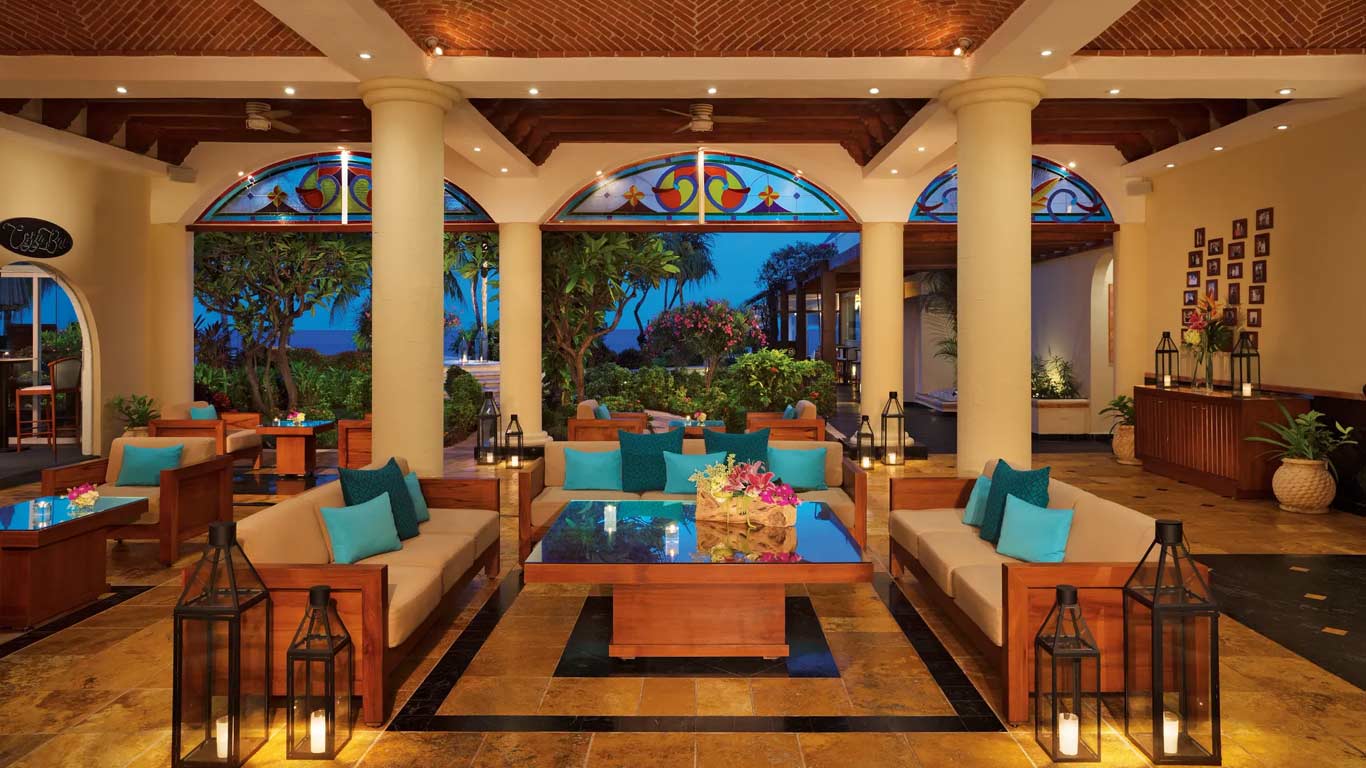 Resort lobby and lounge with stained-glass arches, warm wood furniture, and tropical garden views