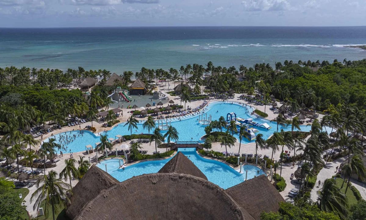 Main swimming pool at Grand Palladium Colonial surrounded by tropical gardens and palm trees