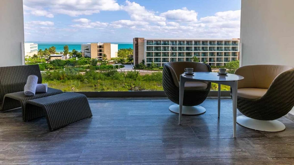 Beachfront view at Grand Palladium Select Costa Mujeres showing wide white sand, crystal-clear Caribbean Sea, and resort facilities