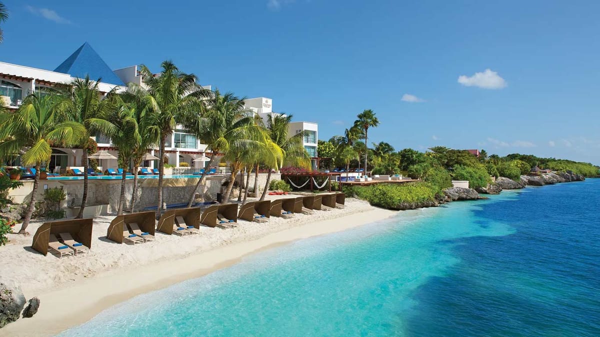 Private beach with wooden privacy screens and blue-cushioned loungers on the Caribbean Sea